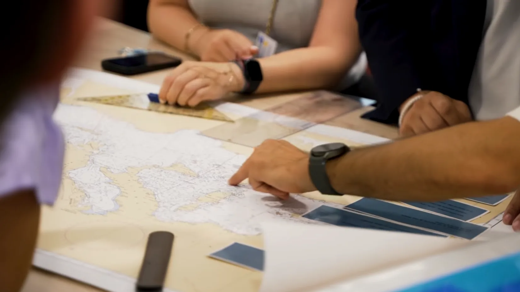Photo d'une session de jeu AIA — participants consultant une carte maritime sur une table